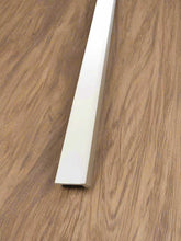 Close-up of a white baseboard against a wooden floor