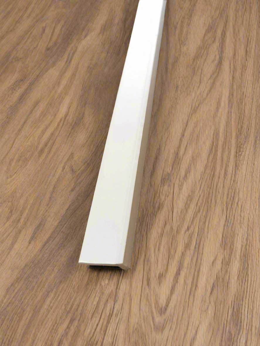 Close-up of a white baseboard against a wooden floor
